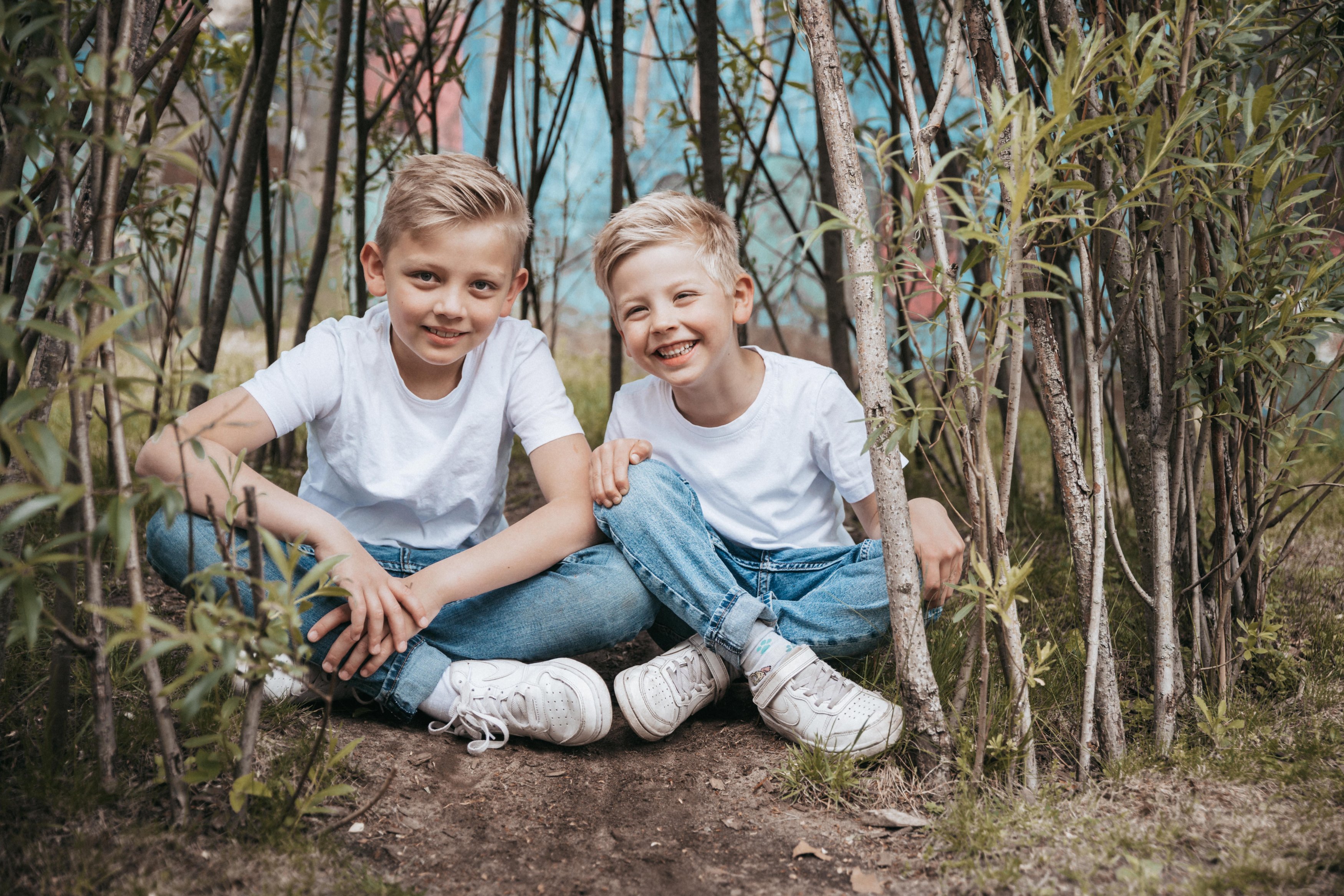 Zwei Jungen sitzen lachend zwischen Weidenzweigen